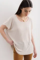 Blusa de tejido de punto fino en color beige con destellos de lurex. Presenta un corte holgado, cuello redondo amplio y mangas cortas con caída relajada.