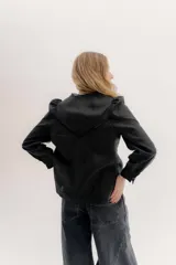 Camisa de lino color beige con mangas abullonadas y detalles de puntilla negra en forma de V en el frente. Presenta cuello a la base con borde desflecado, cierre frontal con botones forrados y puños con alforzas.