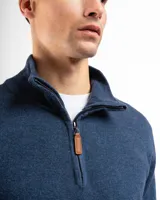 Buzo de tejido de punto negro, con cuello alto y cierre frontal parcial.