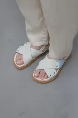 Sandalias planas color celeste y blanco, con tiras anchas cruzadas y suela color caramelo.