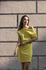 Vestido corto color lima, con escote asimétrico y manga corta.