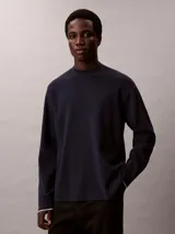 Sweater de corte boxy confeccionado en tejido de punto técnico, con cuello semi alto y mangas largas. Presenta un diseño minimalista y relajado con acabado liso.