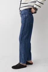 Jean de corte recto y tiro bajo, confeccionado en denim azul clásico. Presenta costuras laterales destacadas y diseño de cinco bolsillos.