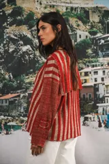 Buzo color beige con rayas horizontales en lurex dorado, cuello con medio cierre, corte oversized y logo tejido en el puño.