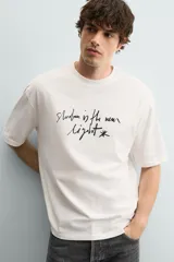 Camiseta de corte relajado confeccionada en algodón, con cuello redondo, manga corta y estampado de texto en contraste en el frente.