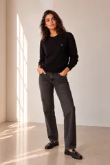 Sweater de punto negro con cuello redondo, manga larga y detalles acanalados en el cuello, los puños y el dobladillo. Presenta un pequeño bordado en el pecho.