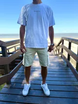 Remera oversize de color beige con estampa en la espalda de una palmera y una tabla de surf, acompañada de la inscripción "Surfer's Paradise Laguna Beach".