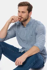 Camisa de lino color beige con cuello mao, manga larga, cierre frontal de botones y bordado sutil en el pecho.