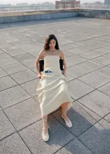 Top strapless color beige, con escote palabra de honor, diseño entallado, fruncido lateral y bajo deshilachado. Cuenta con cierre de cremallera lateral.