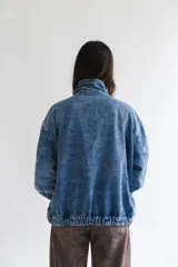 Campera de denim azul con diseño oversize, cuello alto con cierre y bolsillos frontales.