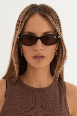 Lentes de sol con armazón ovalado de policarbonato negro y cristales oscuros, diseño clásico con protección UV400.