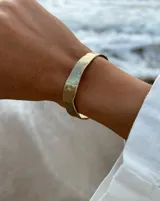 Pulsera tipo esclava abierta con diseño rústico y acabado irregular, fabricada en bronce y alpaca.