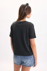 Remera de manga corta color negro con efecto acid wash y estampa frontal de flores en tono dorado brillante. Cuenta con corte clásico y cuello redondo.