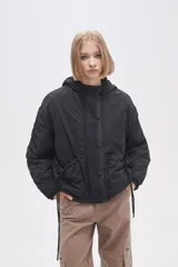 Campera negra de manga larga con capucha, cierre frontal con botones a presión, bolsillos laterales y cordón ajustable en la cintura.