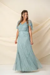 Vestido largo de tul bordado color verde agua, corte a la cintura y falda amplia. Las mangas son desmontables mediante broches, permitiendo usarlo sin mangas y combinarlo con un chal o túnica.