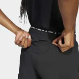 Shorts de running negros para mujer, con tres franjas blancas verticales en los laterales y logo de Adidas en la pierna izquierda. Presenta un logo adicional 'AR' en la pierna derecha.