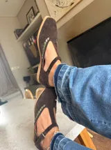 Ballerinas de gamuza color marrón oscuro con diseño tipo T-strap y detalles de costuras decorativas en color verde oliva. Cuentan con cierre de pulsera al tobillo y suela plana.