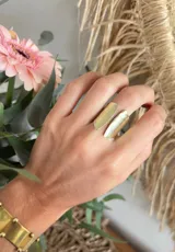 Anillo abierto dorado con dos rectángulos texturados en los extremos.