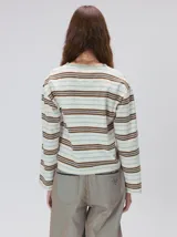 Remera de manga larga con diseño a rayas horizontales en tonos azul, blanco y negro. Presenta un cuello redondo al tono y un logo bordado en el pecho. El diseño destaca por tener un patrón de rayas diferente en las mangas y un calce holgado.