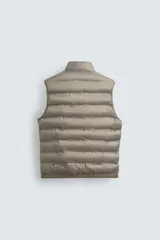 Chaleco acolchado verde oscuro, con cuello alto, cierre frontal con cremallera y bolsillos laterales. Confeccionado en tejido técnico repelente al agua.