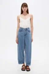 Pantalón slouchy de jean azul, tiro alto, con diseño bordado y calado en el isotipo de las botamangas.