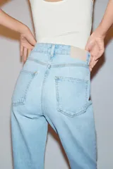 Pantalón jeans Z1975 de tiro alto y diseño mom fit, color azul claro con lavado desgastado, de corte tobillero y cinco bolsillos. Cierre frontal con cremallera y botón metálico.