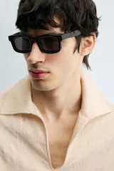 Camisa de manga larga color beige claro con textura jacquard arrugada, cuello solapa con abertura en V y bolsillo canguro frontal. Posee cordones ajustables en el bajo lateral.