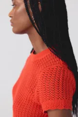 Sweater de punto con tejido de ganchillo color rojo, de manga corta, cuello redondo y diseño con panel de rombos en la parte inferior.