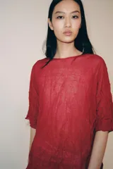 Top rojo de punto con textura efecto arrugado, cuello redondo y mangas cortas holgadas.