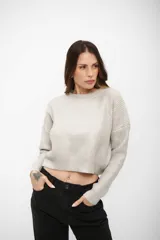 Buzo de tejido de punto con acabado brillante, cuello redondo, mangas largas y corte cropped.