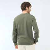 Buzo de cuello redondo verde con textura tipo nido de abeja, mangas largas y puños elastizados.