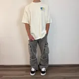 Pantalón de jean estilo cargo con corte baggy, color azul lavado. Presenta cuatro bolsillos laterales de gran tamaño con solapa y cierre de botones, diseño de pierna ancha y tiro medio.
