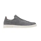 Championes Adidas modelo Stan Smith Nuud, color gris con acabado en gamuza. Presentan un diseño minimalista con suela de goma en color crema y detalles internos en tono rojizo.