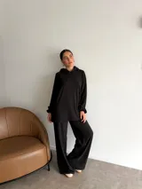 Conjunto de dos piezas compuesto por un buzo con capucha de corte holgado y mangas largas, y un pantalón de corte recto y tiro alto. Ambas prendas son de color marrón liso.