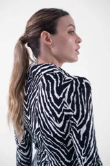 Vestido midi de corte ajustado, con estampado animal print tipo cebra en blanco y negro, cuello camisero, escote en V y cierre frontal con botones dorados.