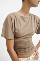 Camiseta de manga corta color marrón topo con cuello redondo y detalle de drapeado lateral.