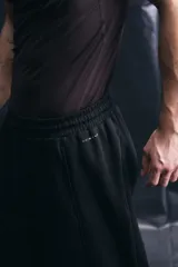 Pantalón de jogging deportivo de corte holgado, confeccionado en tejido técnico con tecnología de absorción de humedad. Presenta cintura elástica con cordón de ajuste, bolsillos laterales, ribetes verticales en las piernas y cordón elástico ajustable en los bajos.