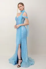 Vestido largo de fiesta en tul bordado con lentejuelas celestes, silueta ceñida, escote con tirantes caídos y tajo frontal.
