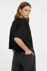 Remera blanca de corte holgado con mangas 3/4 y cuello redondo a la base. Presenta un diseño con apliques de studs metálicos distribuidos por toda la prenda.