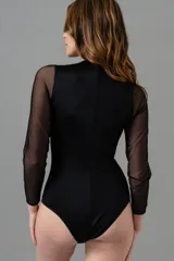 Body negro de lycra y microtul, con mangas largas de microtul y detalle en la cintura.
