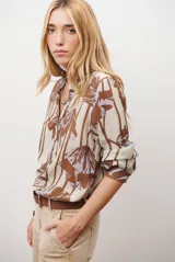 Camisa de manga larga con estampado floral en tonos marrones y negros, cuello mao y cierre frontal parcial con botones.