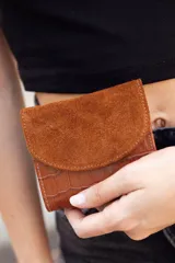 Billetera marrón de cuero con textura tipo cocodrilo en la parte inferior y solapa de gamuza en la parte superior.