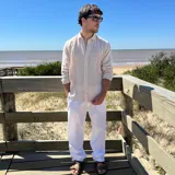 Camisa de manga larga color beige claro, con textura de lino arrugado y corte boxy. Presenta cuello camisero y cierre frontal de botones.