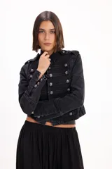 Chaqueta de jean estilo napoleónico color negro, con cuello mao, hombreras y filas dobles de botones metálicos grabados.