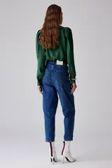 Pantalón de jean azul índigo, tipo cargo, con bolsillos laterales, de tiro medio, con botón negro metálico y diseño de boca en el bolsillo.