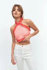 Top de escote halter confeccionado en broderie de algodón y bordado con hilo color coral. Enmarcado con voladitos de lino a tono.