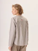 Camisa de corte recto y manga larga, con diseño a rayas verticales y detalle de volados en el frente. Confeccionada en algodón.