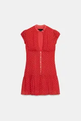 Vestido corto rojo con estampado de lunares blancos, cuello redondo con escote en pico pronunciado, manga muy corta y cierre frontal con botones.