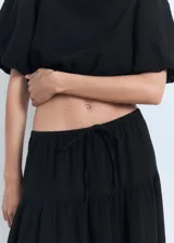 Falda larga evasé de tiro bajo y color negro, confeccionada en tejido 100% algodón, con cintura elástica y cordón ajustable.