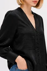 Camisa negra de poliéster satinado, de corte holgado, con cuello en V, cierre frontal abotonado y mangas largas con puños estructurados.